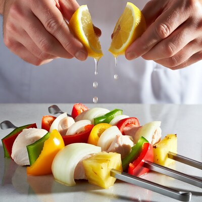 Hands squeezing lemon over kabobs