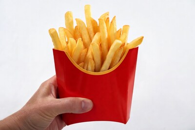 Hand holding french fries in red carton