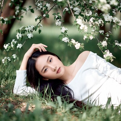 Asian woman lying in grass under flowers