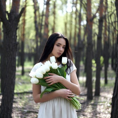 Woman holding white tulips in forest