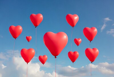 Red heart balloons floating in sky