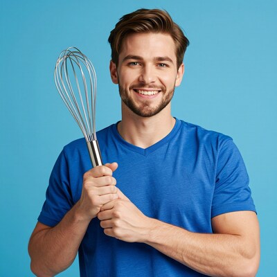 Smiling man holding kitchen whisk