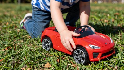 Child playing with red toy sports car