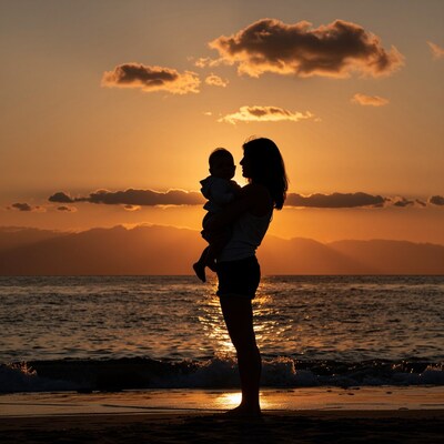 Mother holding baby at sunset beach