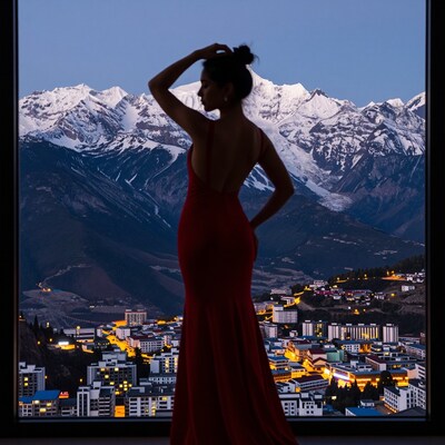 Woman in red dress overlooking snowy mountains