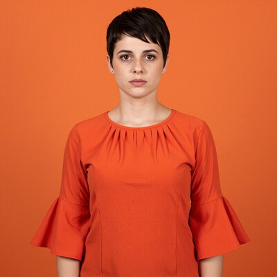 Woman with short pixie haircut in orange top