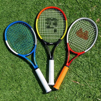 Three colorful tennis rackets on grass
