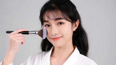 Asian woman applying makeup with brush
