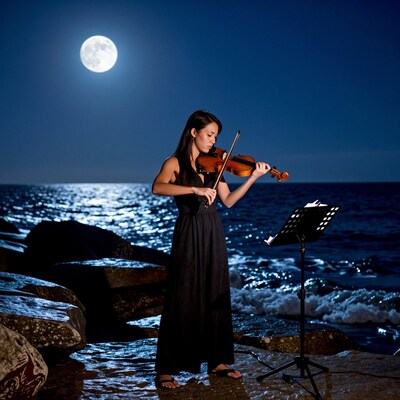 Woman playing violin by moonlight sea